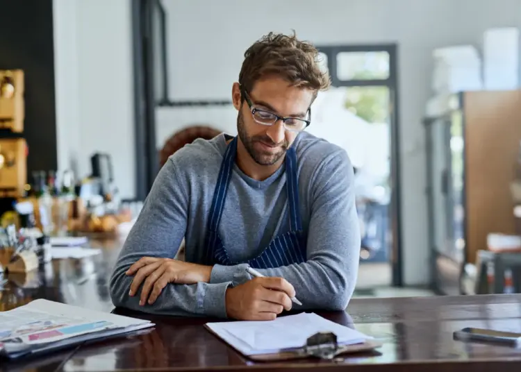 man with blonde hair writes on clip board