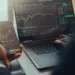 person using laptop and phone for stock analysis
