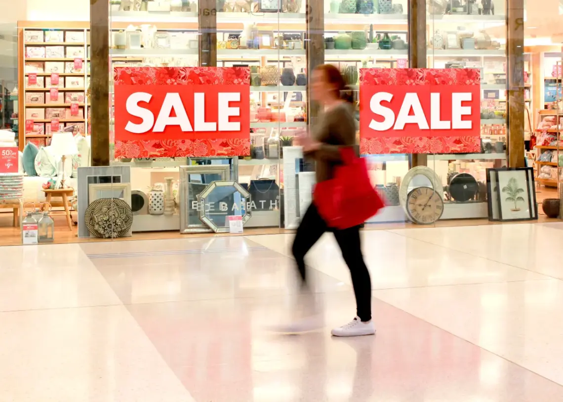 woman walking past a retail store displaying sale
