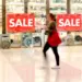 woman walking past a retail store displaying sale