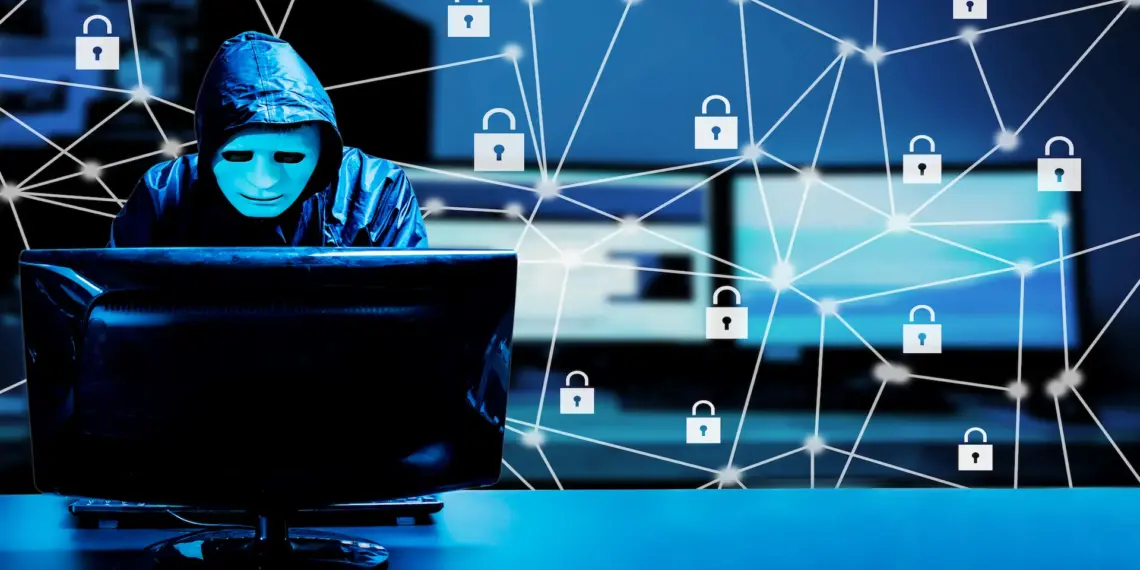 hooded hacker working on computer in dark