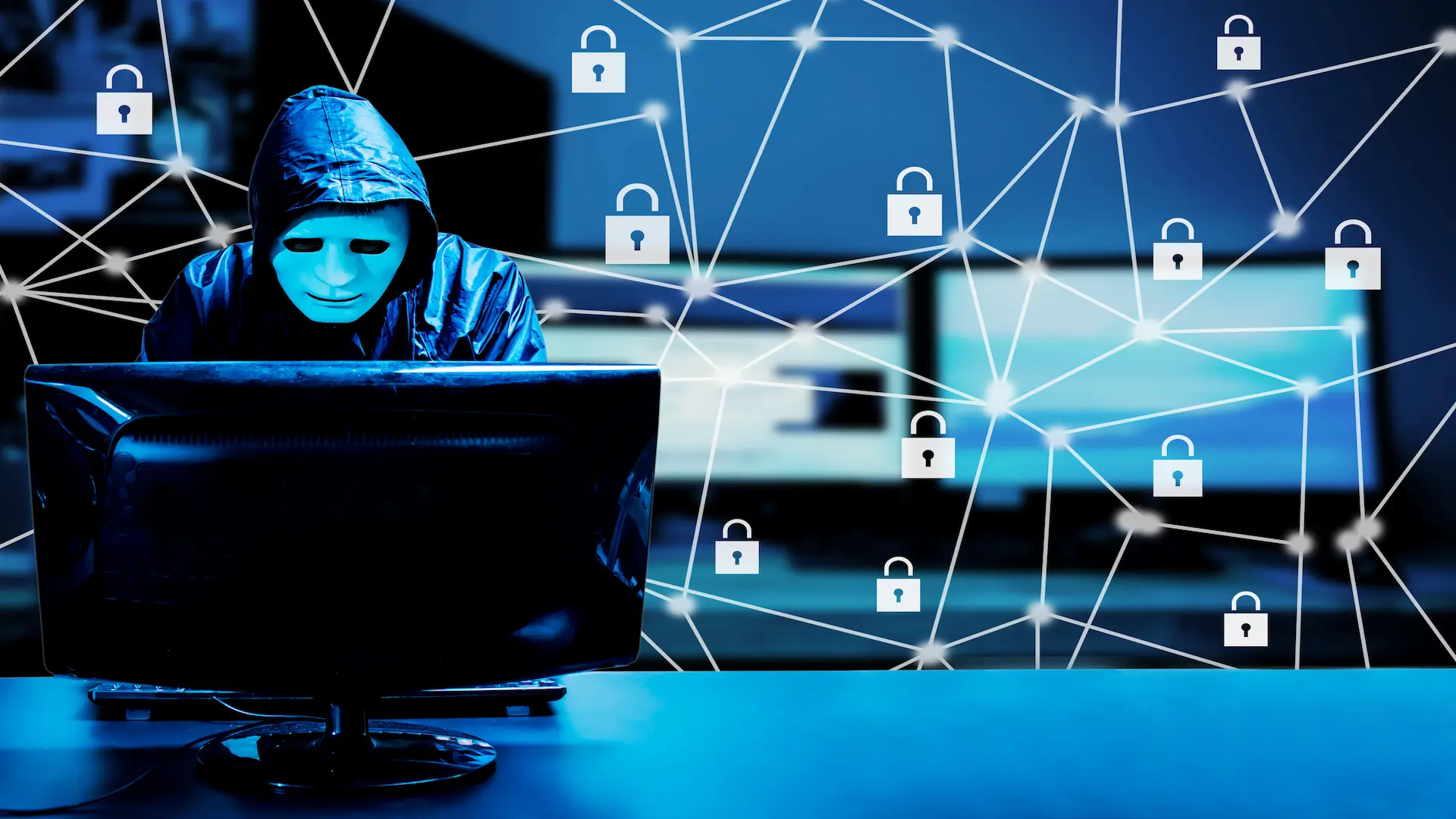 hooded hacker working on computer in dark