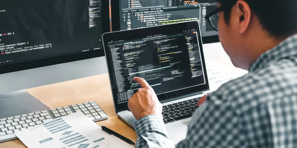 software developer working at desk with multiple