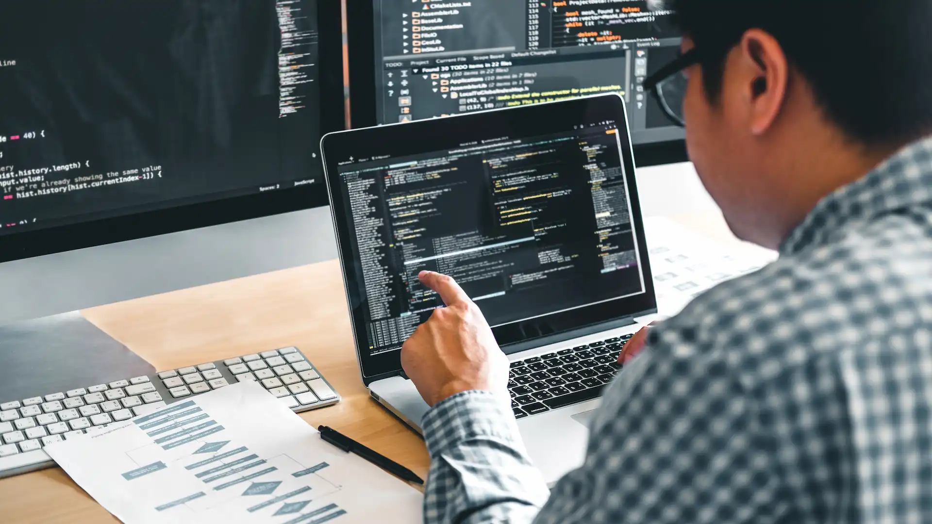 software developer working at desk with multiple