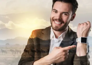 smiling young man pointing at smartwatch device